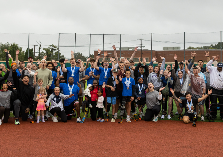 Participants, athletes, volunteers, and supporters gather on a track and field at a Challenged Athletes Foundation and Össur adaptive sports clinic in Washington, D.C.