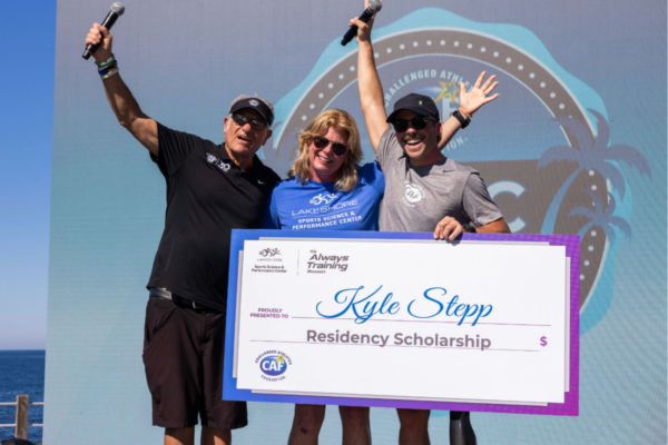 Photo of kyle stepp on main stage posing for a photo with caf co founder bob babbitt accepting his grant