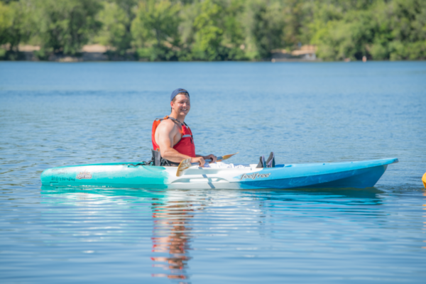 Andrew Kurka paddles a kayak across a lake, showcasing year-round participation in outdoor recreation and adaptive sports.