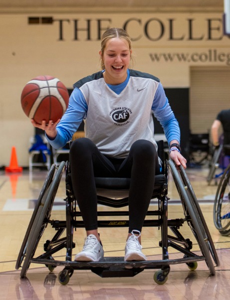 A woman in a wheelchair dribbling a basketball